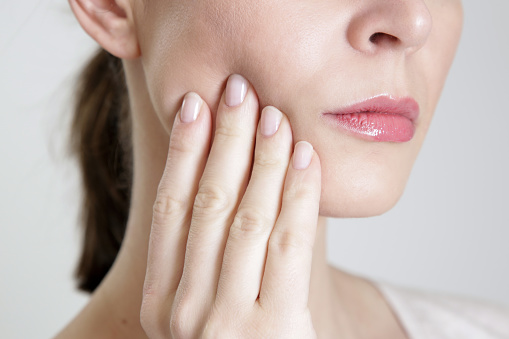 Woman holding her jaw in pain needs to make an appointment at Peak Endodontics in Covington, WA