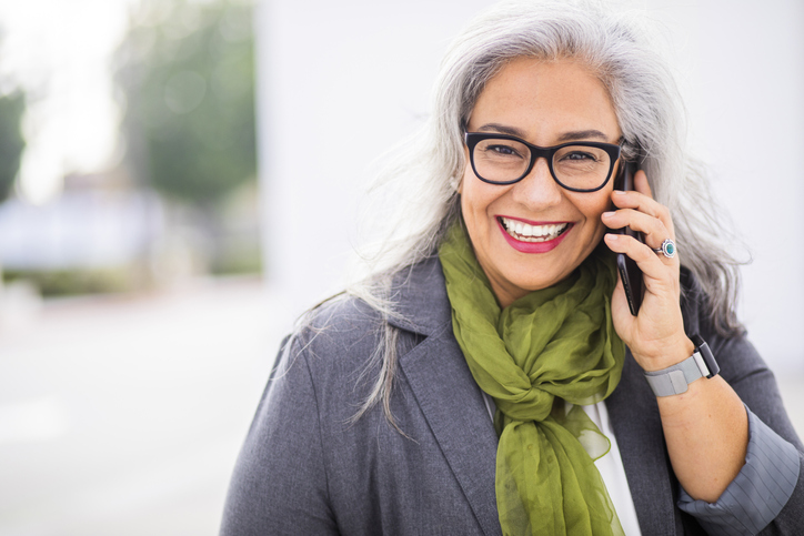 A smiling patient contacting Peak Endodontics on a cell phone.