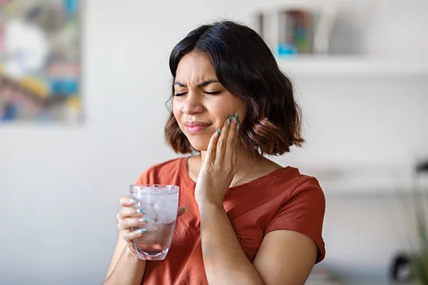 Woman drinking cold water and feeling pain from a cracked tooth